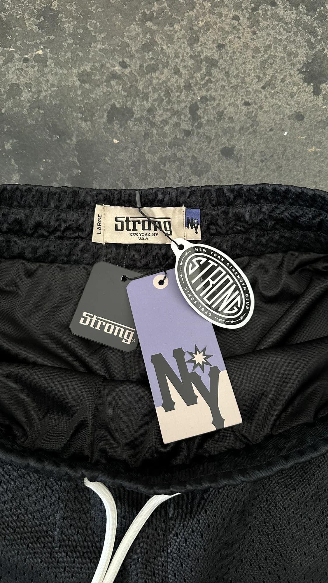 Black Strong New York mesh shorts with a white drawstring and branded tags