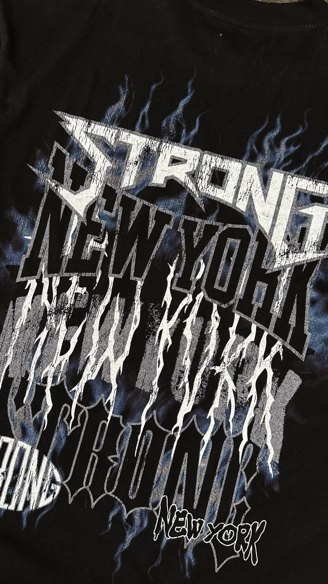 Close-up of layered Strong New York lettering and blue graphics on a black tee